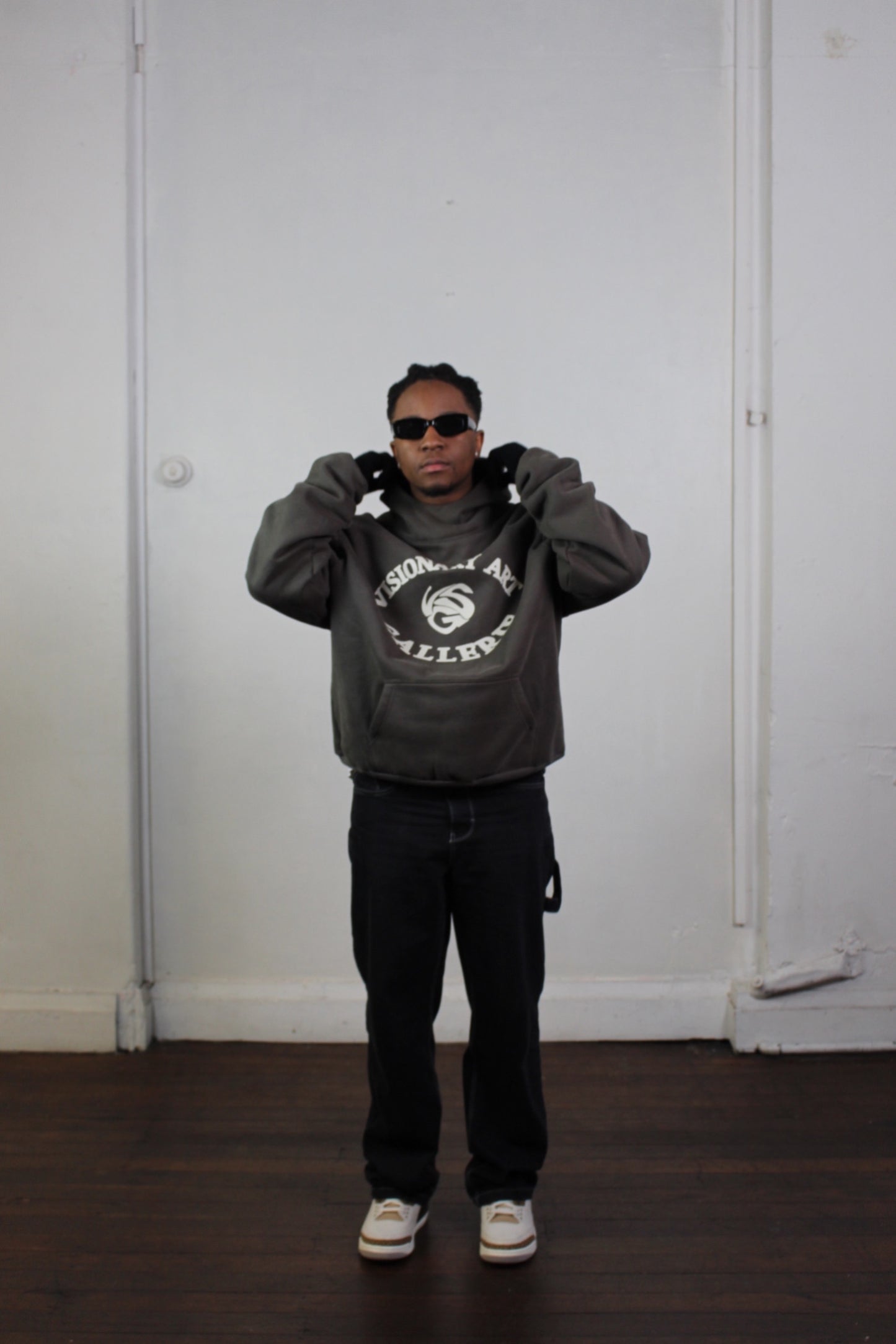 Model posing with Vision studios' Visionary art gallerie hoodie in charcoal green and cream (size M)