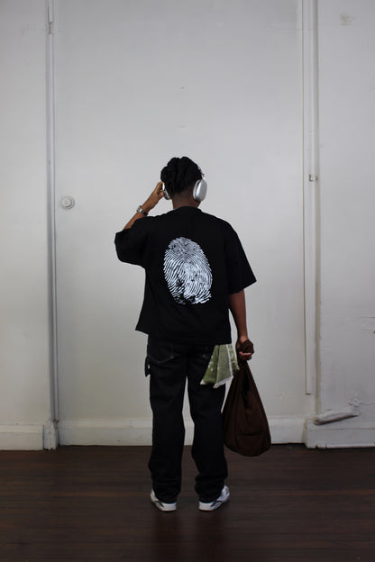 Back view of model wearing black oversized drop shoulder t-shirt featuring distressed thumbprint graphic inspired by Genesis 1:26-27
