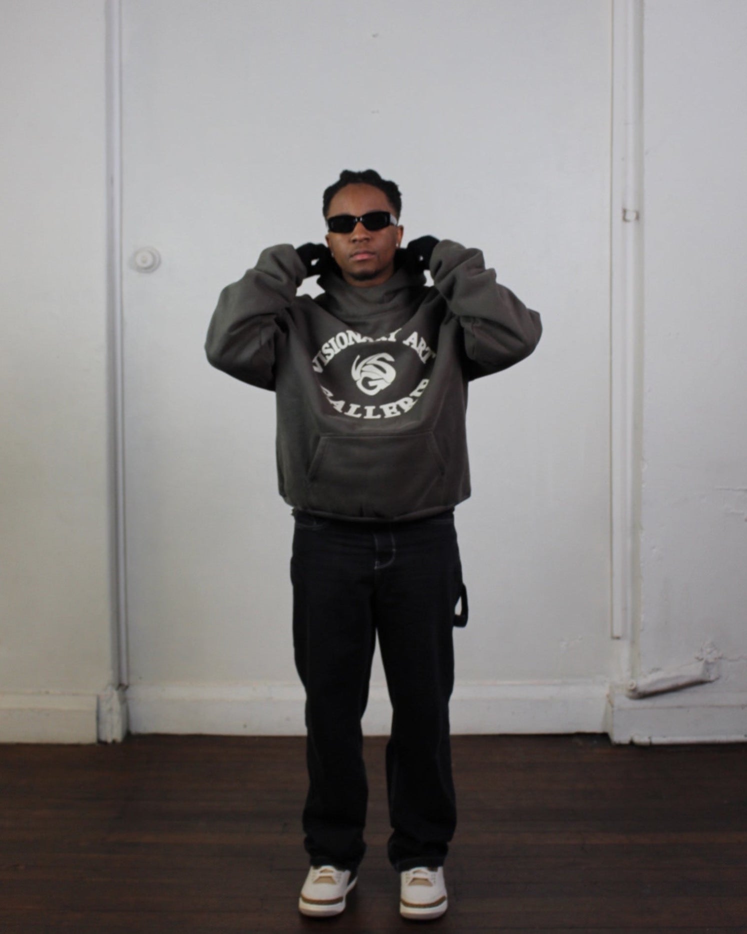 Model posing with Vision studios' Visionary art gallerie hoodie in charcoal green and cream (size M)