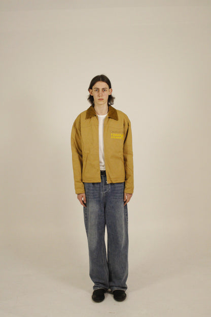 front view of model wearing SAMPLE_001 canvas utility jacket unzipped with embroidered Vision Studios logo, showing cropped workwear fit and structured silhouette