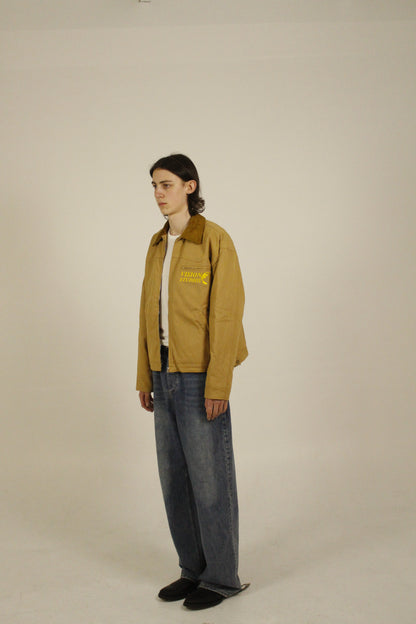 Side view of model wearing SAMPLE_001 canvas utility jacket unzipped with embroidered Vision Studios logo, showing cropped workwear fit and structured silhouette