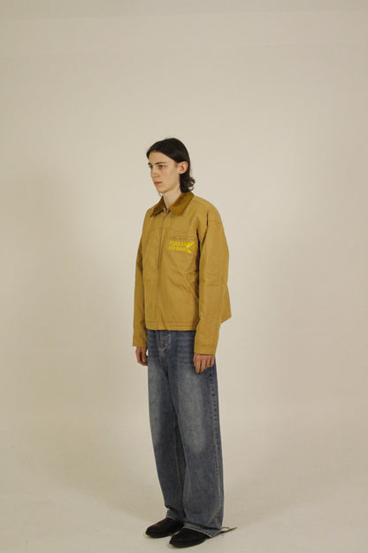 Side view of model wearing SAMPLE_001 canvas utility jacket with embroidered Vision Studios logo, showing cropped workwear fit and structured silhouette