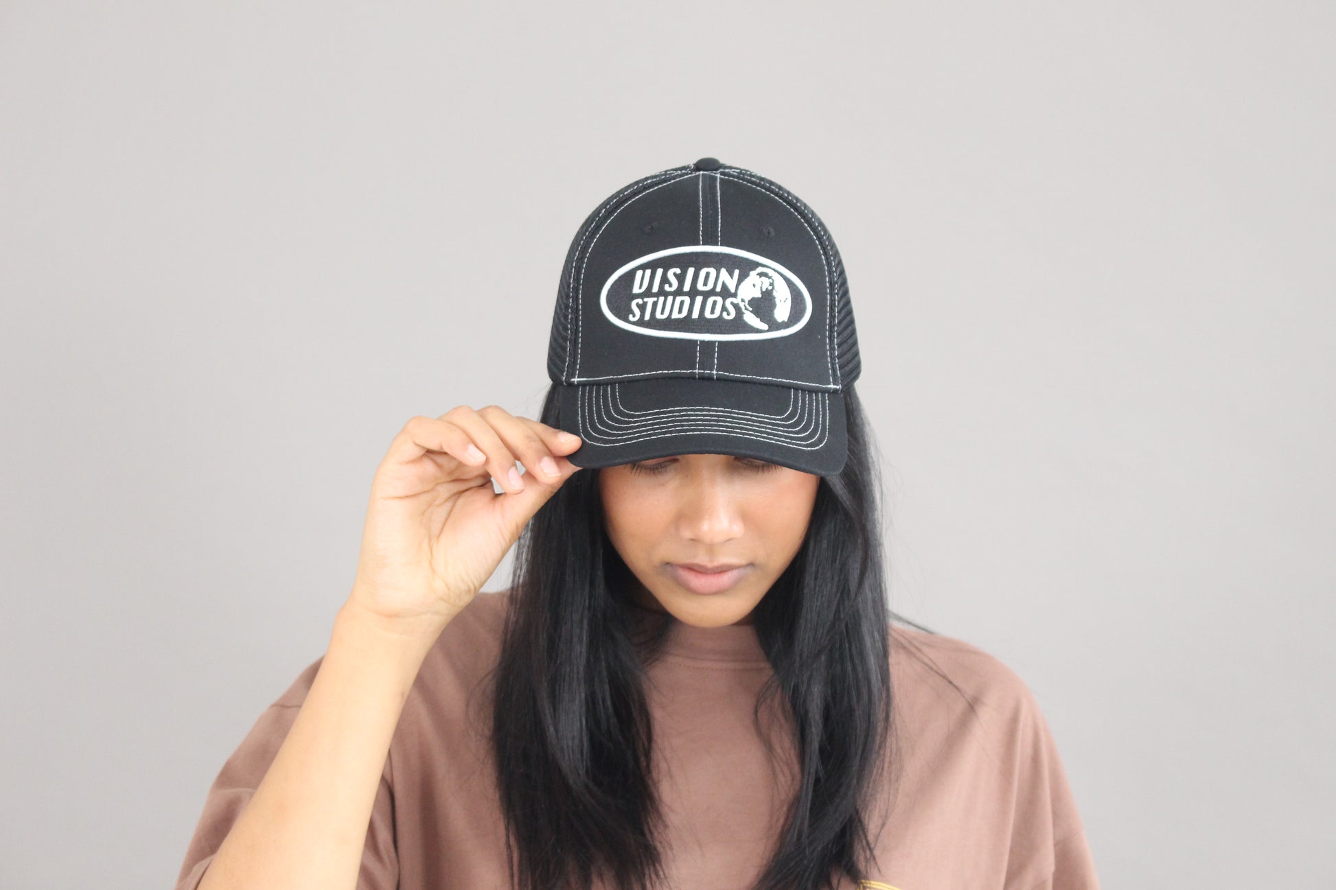 A female model posing with the black vision studios trucker hat