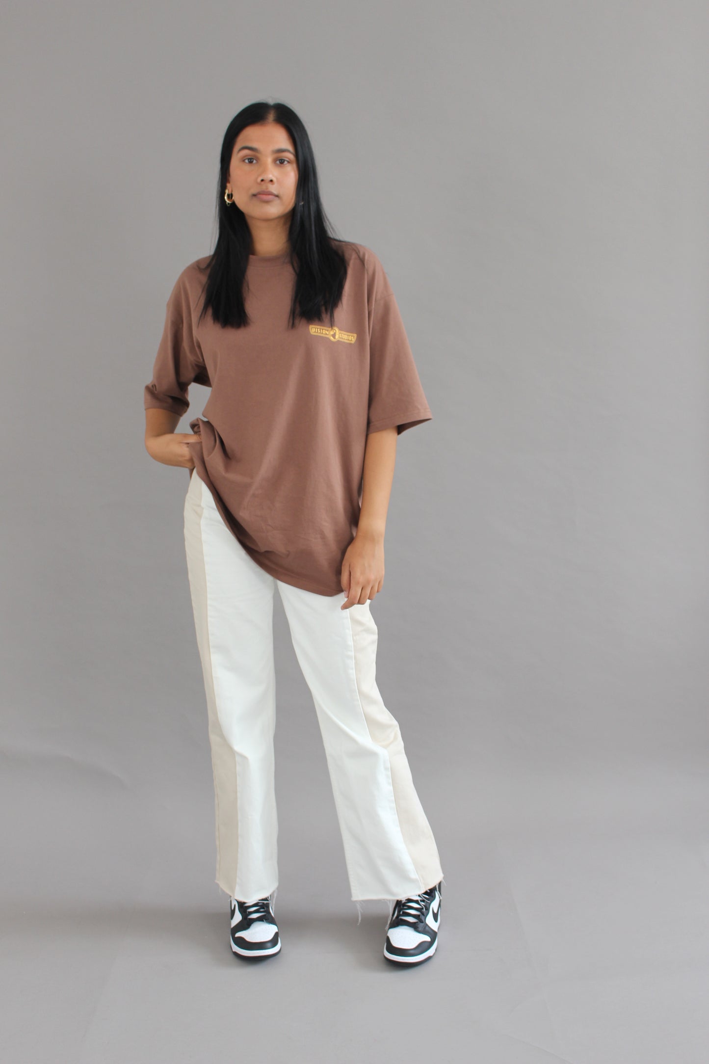 A female model posing with vision studios walnut brown oversized tee (size XL)